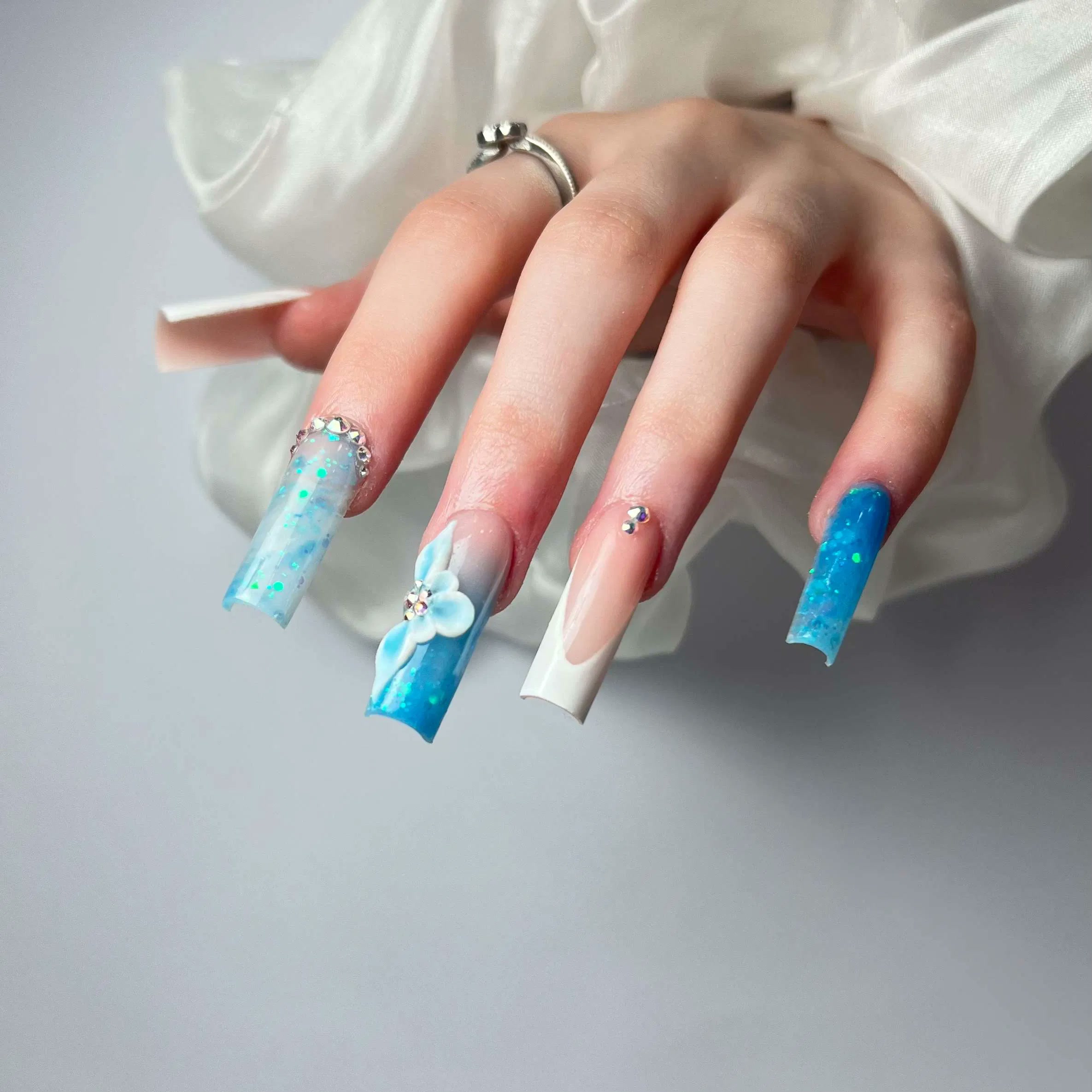 Long blue and white nails with embellished details at Aurevia Nails